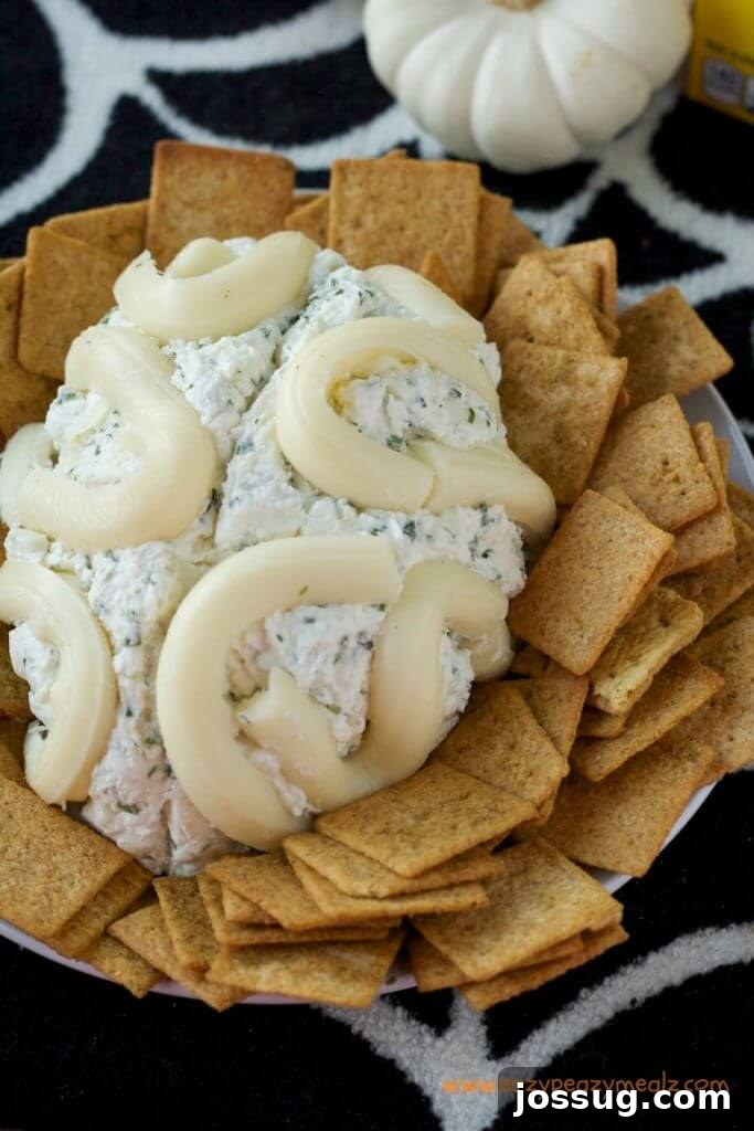 A realistic brain-shaped cheeseball, served with mini crackers for dipping.