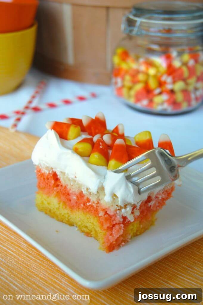 A delightful Candy Corn Poke Cake, featuring the iconic yellow, orange, and white layers soaked in flavorful liquid.