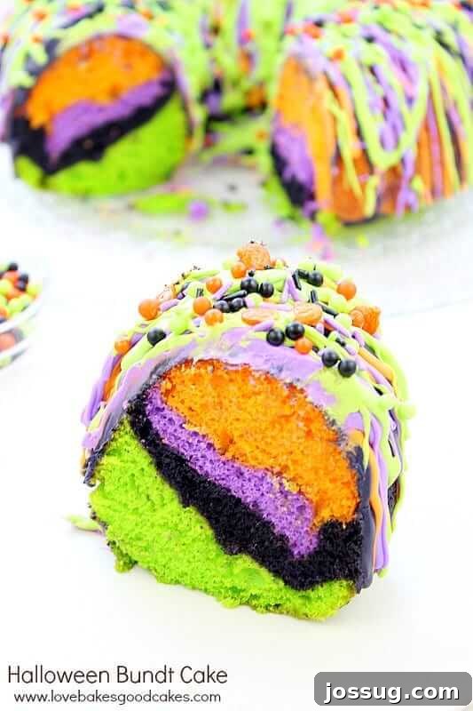 A festive Halloween Bundt cake with a slice removed, revealing layers of colorful cake inside.
