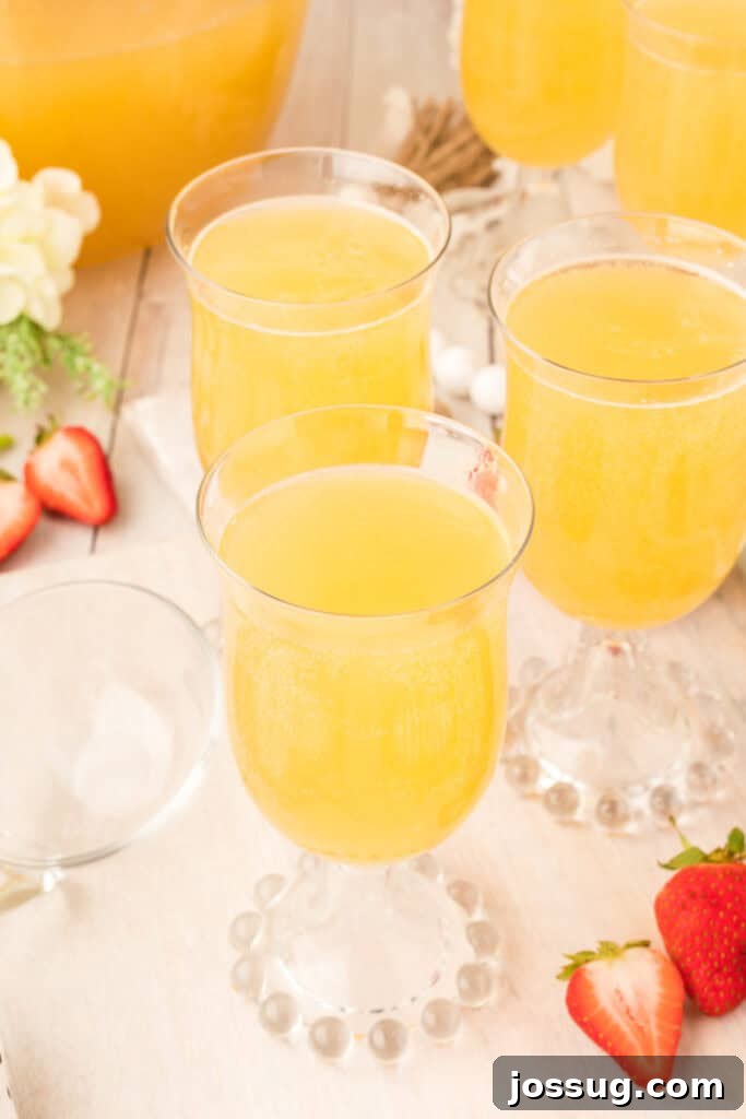 Sparkling Celebration Punch 2 Close-up of glasses filled with bubbly mock champagne punch garnished with strawberries and surrounded by fruit.
