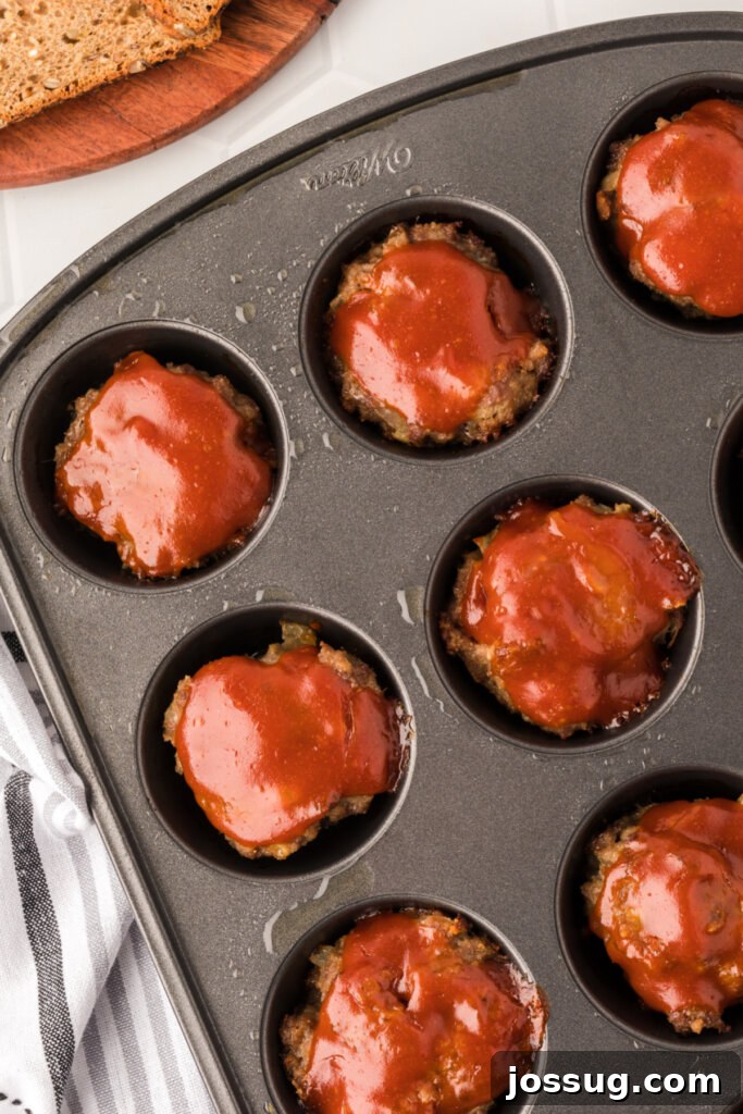 Meatloaf Minis 2 Perfectly baked meatloaf muffins nestled in a muffin tin, showcasing their golden-brown glaze and inviting aroma, ready to be served for a quick weeknight meal.