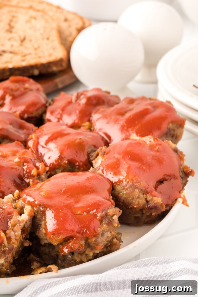 Meatloaf Minis 3 Beautifully arranged finished meatloaf muffins on a white plate, garnished with fresh herbs, ready to be enjoyed as a savory and satisfying dish.
