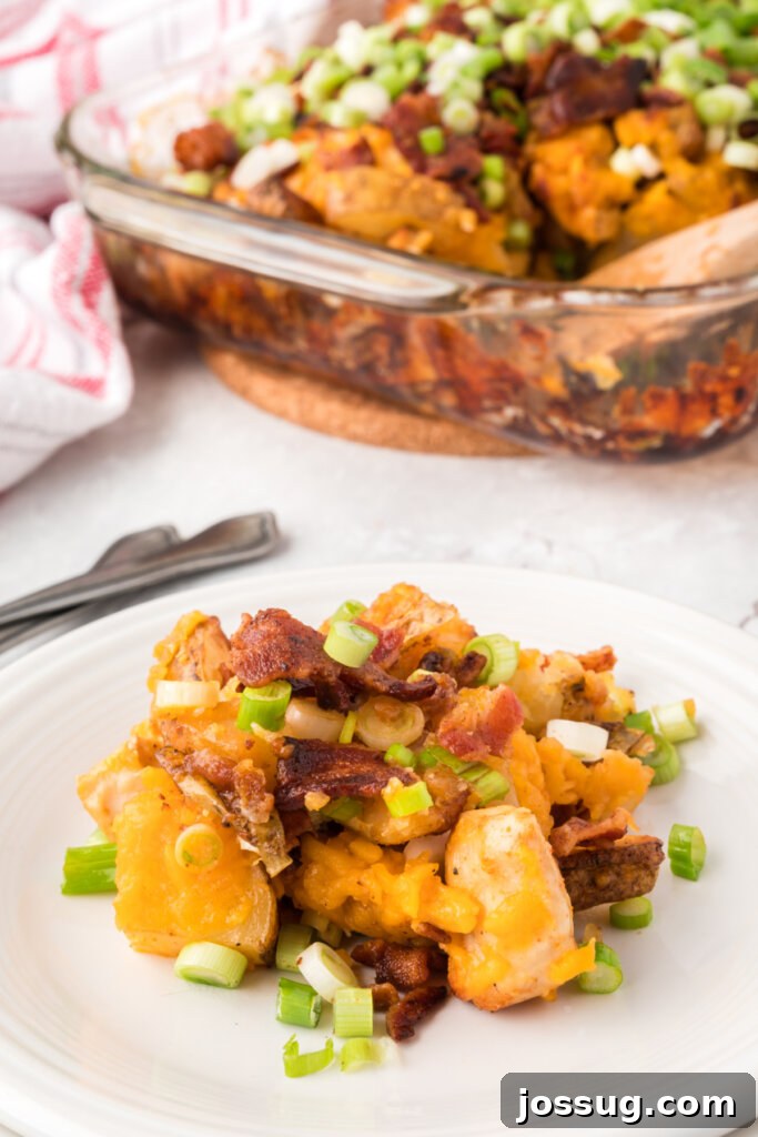 Fully Loaded Chicken Potato Bake 4 A scoop of Loaded Baked Potato and Chicken Casserole served on a plate, garnished with green onions and bacon