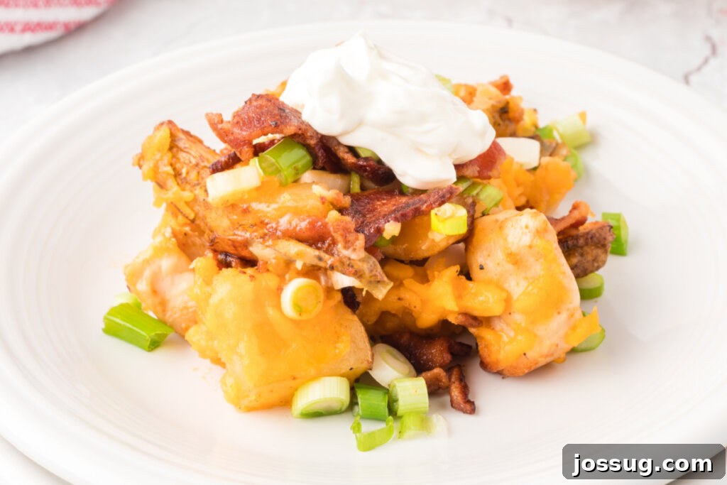 Fully Loaded Chicken Potato Bake 5 A serving of chicken potato casserole on a white plate, showing melted cheese and green onions