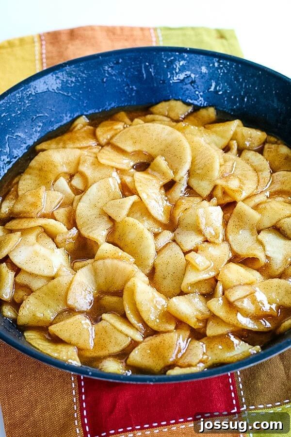 Cooked apples simmering in a skillet, coated in a sweet, spiced sauce.