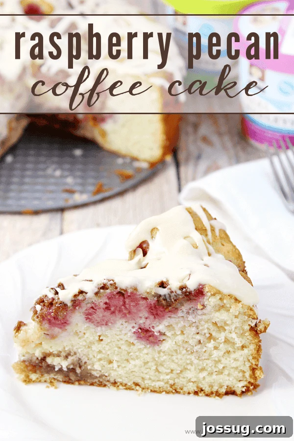 A slice of Raspberry Pecan Coffee Cake on a white plate with a fork, showing its tender crumb, fresh raspberries, and crunchy pecan topping.