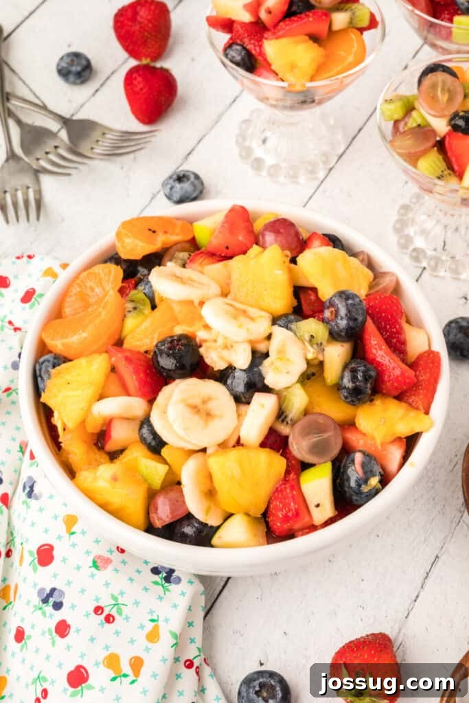 Vibrant Fruit Mosaic with Zesty Honey Glaze 2 Colorful Rainbow Fruit Salad with Honey Citrus Dressing in a white bowl, garnished with mint.