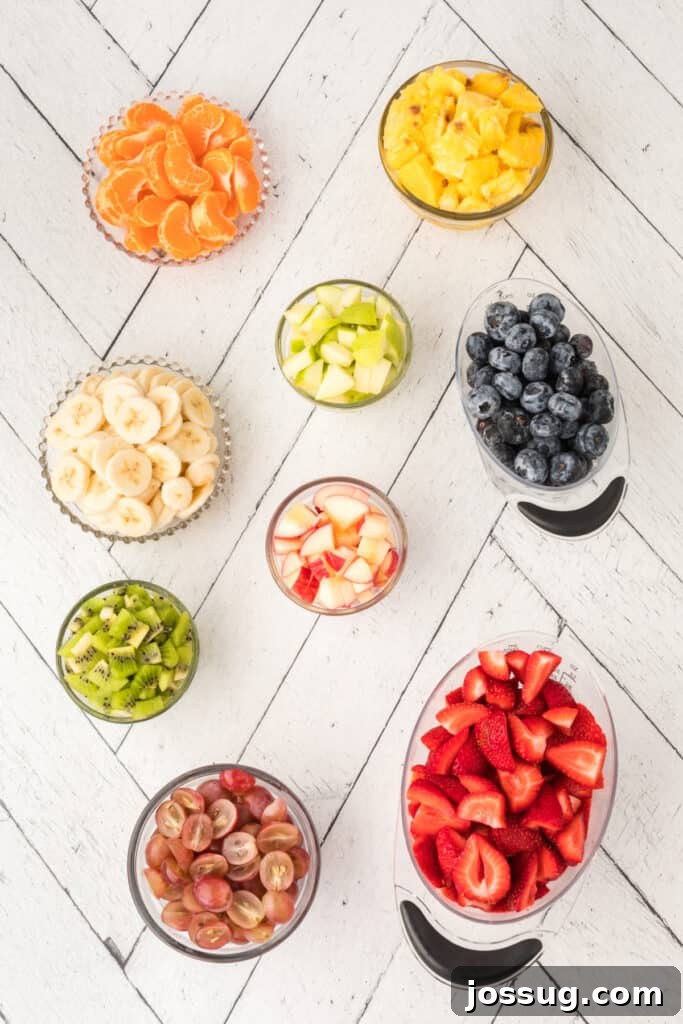 Vibrant Fruit Mosaic with Zesty Honey Glaze 3 Various fresh fruits laid out on a white surface, ready to be chopped for the salad.