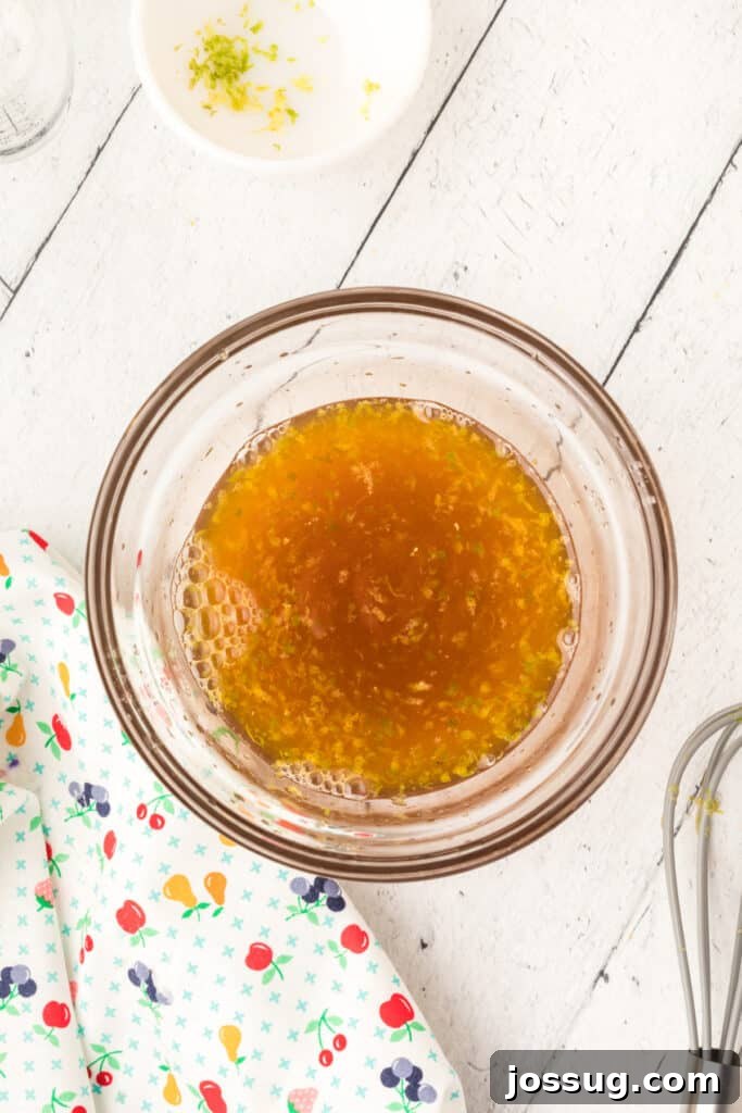 Vibrant Fruit Mosaic with Zesty Honey Glaze 7 Honey being drizzled into the citrus juice mixture and whisked.