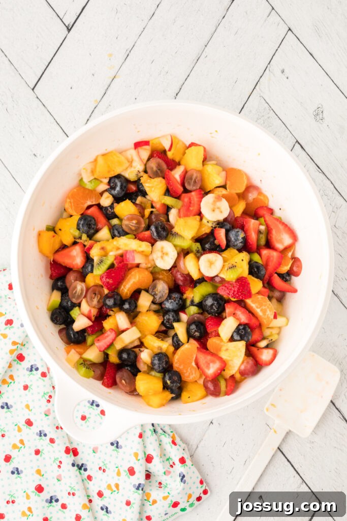 Vibrant Fruit Mosaic with Zesty Honey Glaze 8 Honey citrus dressing poured over the mixed fruit in a bowl and stirred.