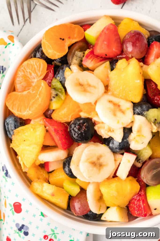 Vibrant Fruit Mosaic with Zesty Honey Glaze 9 Super close-up shot of the colorful fruit salad in a white bowl, showing the vibrant textures.
