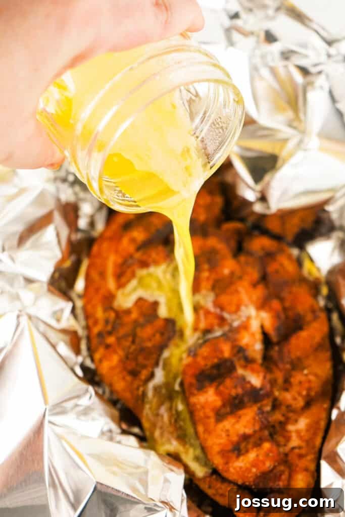 Pouring melted butter over smoked turkey breast in foil
