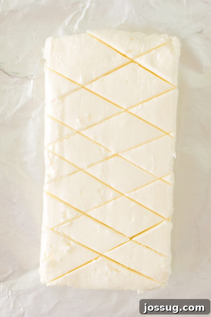 Cream cheese block scored in a crisscross pattern on foil
