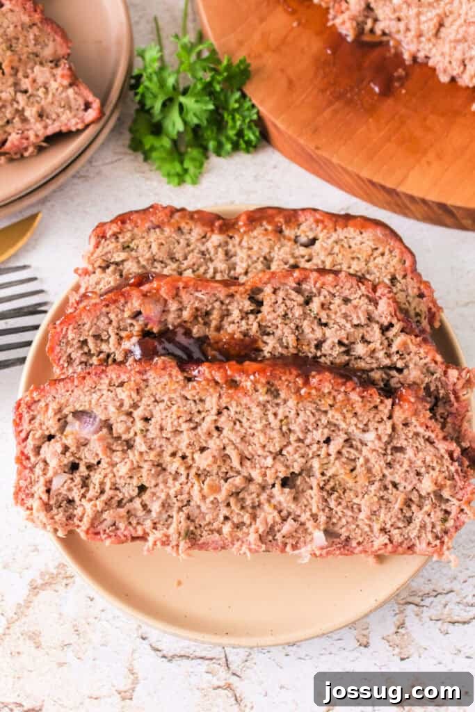 Pit Smoked Meatloaf 2 Overhead view of three perfectly sliced portions of smoked meatloaf stacked on a rustic plate, garnished with fresh parsley.