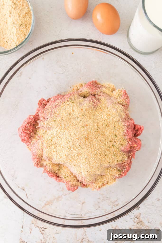 Pit Smoked Meatloaf 5 Italian breadcrumbs being added to the seasoned ground beef mixture, preparing for the next stage of binding and texture.