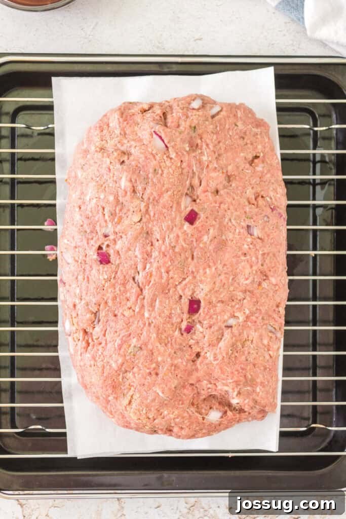 Pit Smoked Meatloaf 7 The uncooked meatloaf expertly shaped into a uniform loaf and placed on parchment paper over a sturdy wire rack, ready for the smoker.
