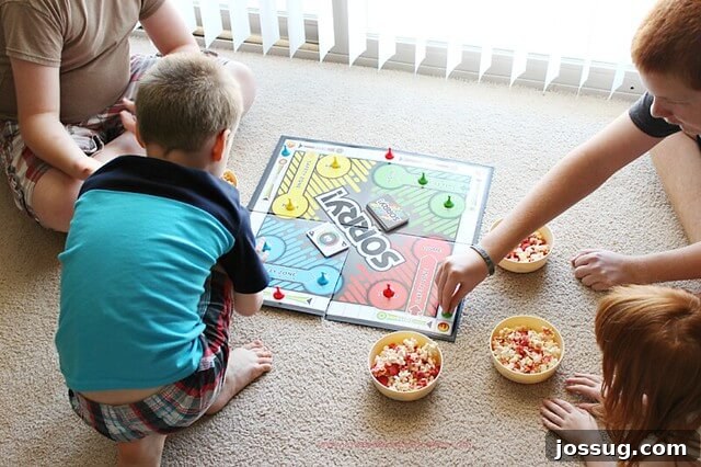 Four children enthusiastically playing a board game on a living room floor, sharing a bowl of popcorn and creating joyful memories.