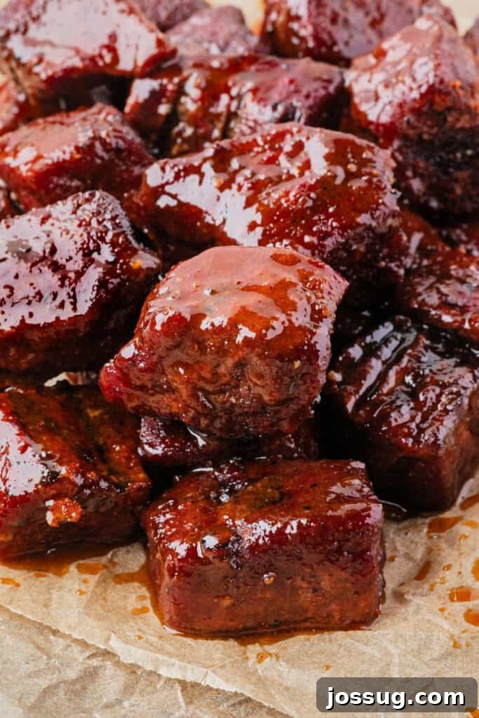 Burnt Ends on a Budget 2 Close-up of saucy Poor Man’s Burnt Ends on parchment paper, glistening with BBQ glaze, ready to be served.