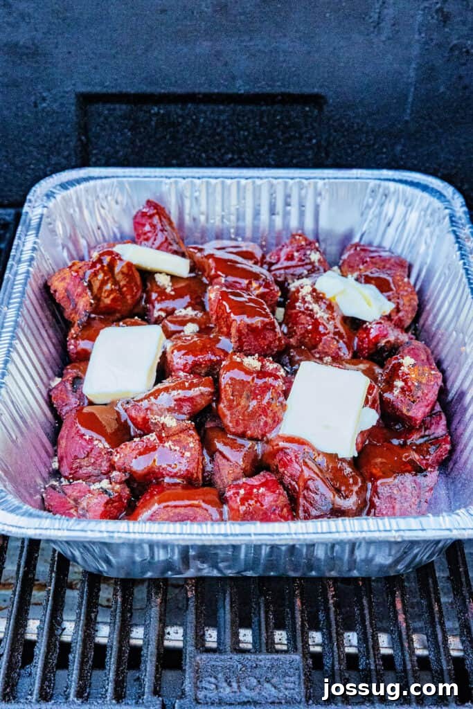Burnt Ends on a Budget 7 Foil pan of smoked burnt ends topped with butter, brown sugar, and BBQ sauce before covering, ready for the braising stage.