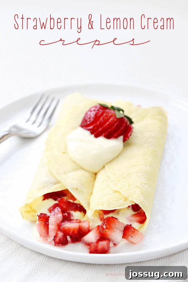 Strawberry & Lemon Cream Crepes on a white plate with a fork, garnished with fresh berries and lemon zest.