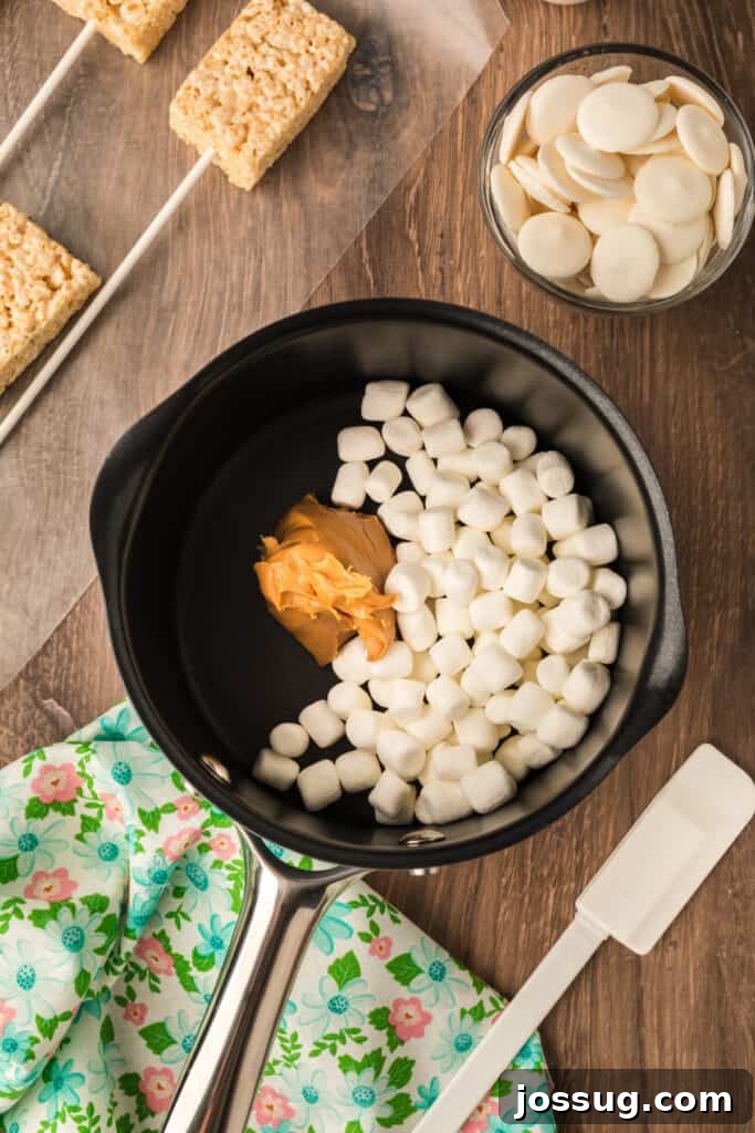 A small saucepan containing creamy peanut butter and a handful of mini marshmallows, about to be melted together over low heat for the marshmallow coating.