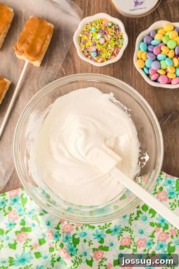 A bowl of smooth, perfectly melted white candy melts, ready for dipping the prepared Rice Krispies Treats Pops.