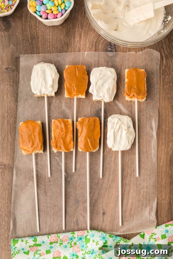 Three of the eight Rice Krispies Treats Pops, now beautifully coated with a layer of glistening white candy melts, resting on waxed paper as they begin to set.