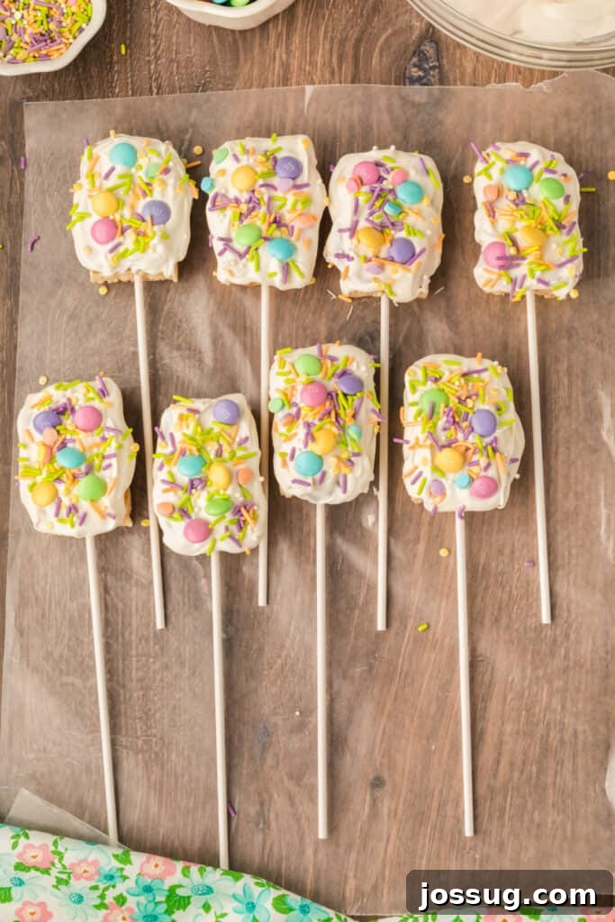 A trio of finished Spring Rice Krispies Treats Pops, elegantly decorated with colorful confetti sprinkles and pastel M&M's, showcasing their festive appeal.