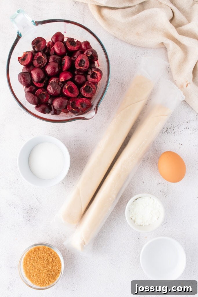 Sweet Cherry Pie Bars 3 Overhead shot of all cherry pie bar ingredients including frozen cherries, packaged pie crusts, an egg, granulated sugar, and cornstarch laid out on a white counter