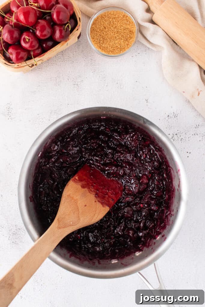 Sweet Cherry Pie Bars 5 Thick cherry pie filling cooking in a saucepan with a wooden spatula