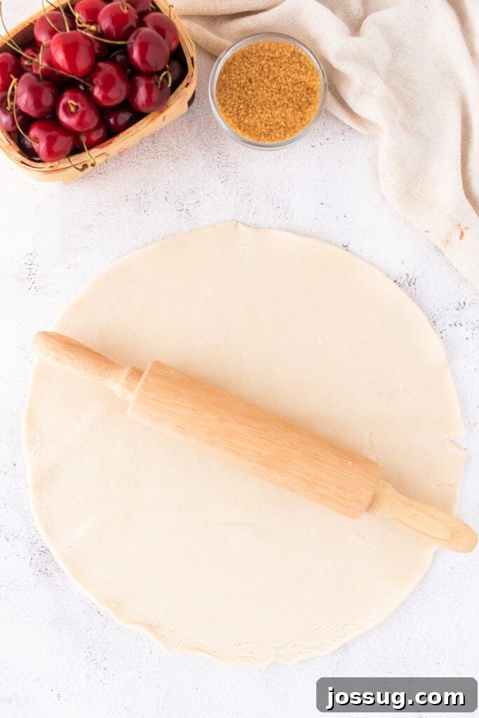 Sweet Cherry Pie Bars 6 Rolled out pie crust with a wooden rolling pin on a white surface