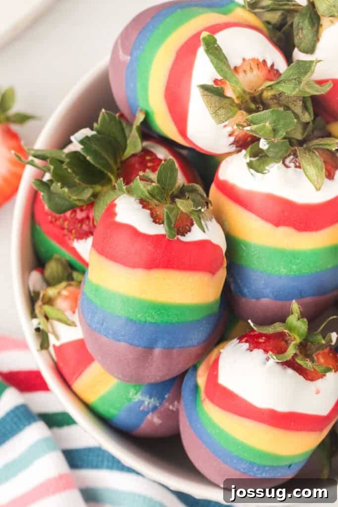 A bowl filled with an assortment of rainbow candy coated strawberries, showcasing their vibrant colors and appealing sheen.