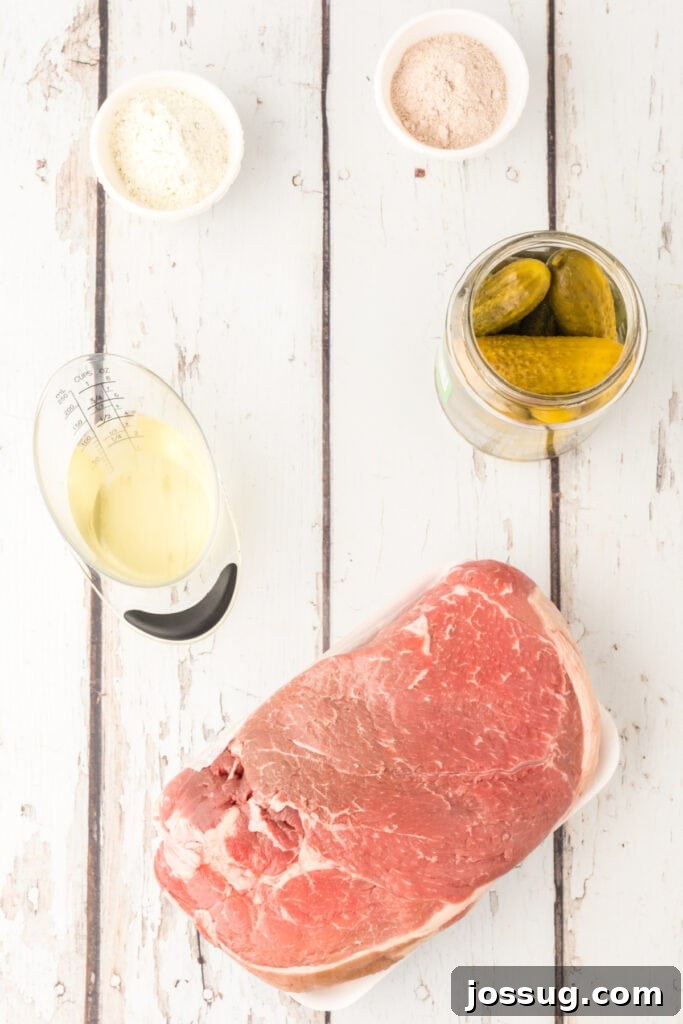 Zesty Slow Cooker Pot Roast 3 Raw ingredients for Slow Cooker Dill Pickle Pot Roast laid out: a large chuck roast, a packet of dry ranch mix, a packet of brown gravy mix, a jar of baby dill pickles, and a small glass of reserved pickle juice.