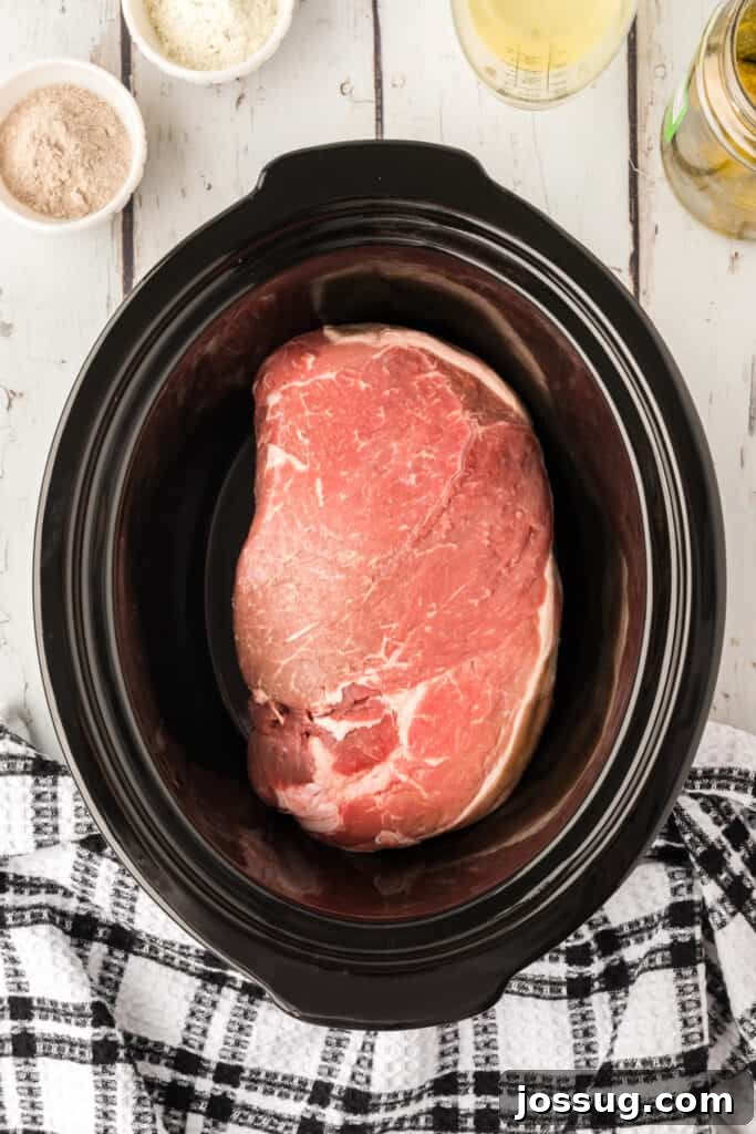 Zesty Slow Cooker Pot Roast 4 Raw chuck roast placed inside a black slow cooker crock, ready for seasoning.