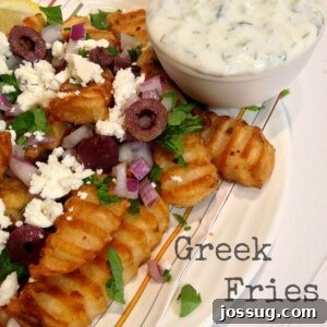 Crispy Greek Fries topped with fresh herbs, red onion, olives, and feta, ready to be served.