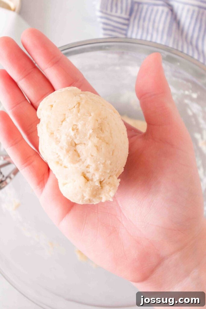 Amazing 3 Ingredient Scones 7 A hand gently holding one portion of scone dough, expertly shaped into a neat, round ball, ready to be placed on a baking sheet.