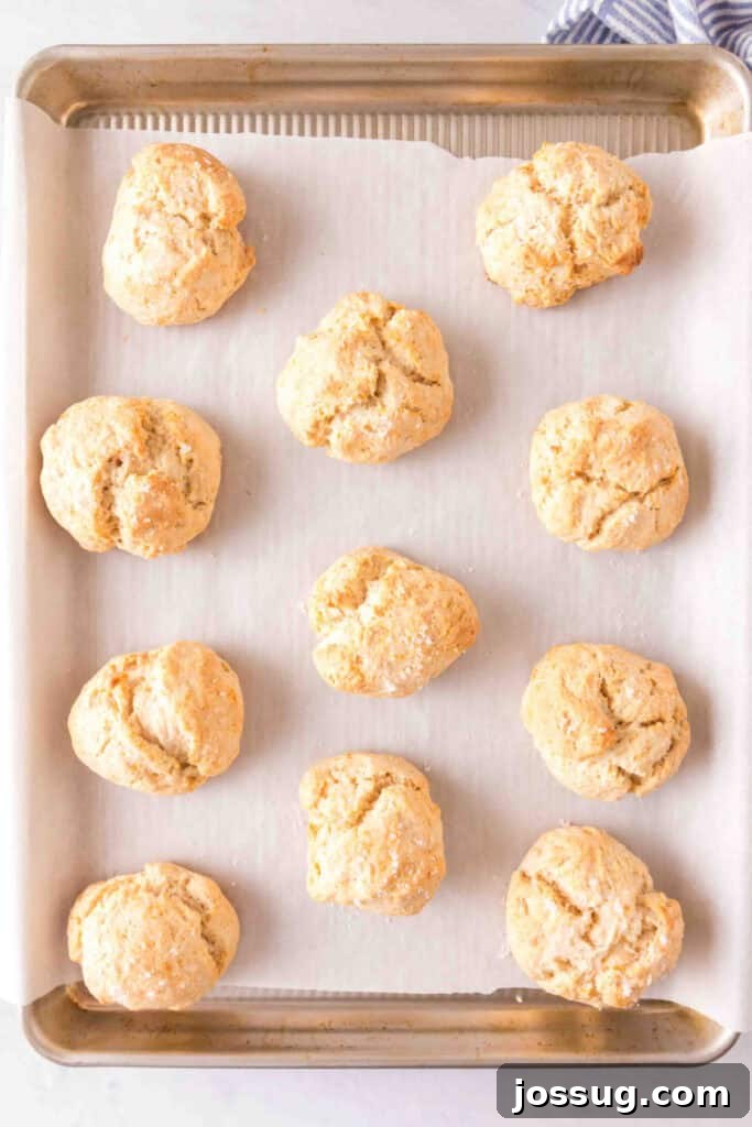 Amazing 3 Ingredient Scones 9 A baking sheet filled with freshly baked, golden-brown scones cooling on a parchment paper liner, displaying their fluffy texture and inviting aroma.