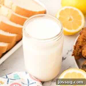 Jar of buttermilk substitute with bread, lemons, and fried chicken, showcasing its versatility.