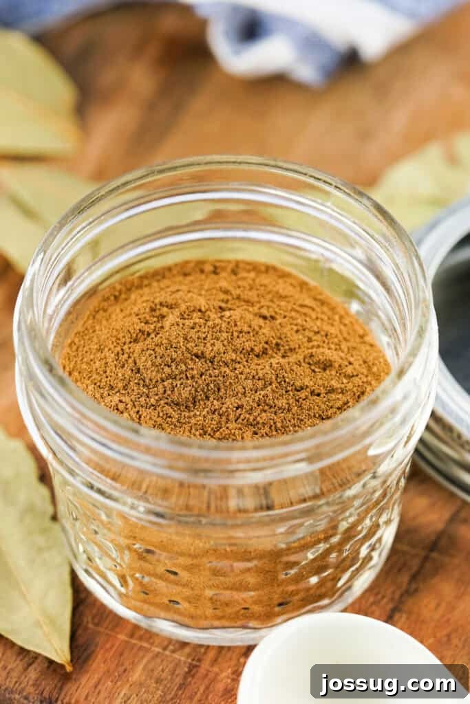 Small mason jar filled with homemade apple pie spice on a rustic wooden surface, exuding warmth and coziness
