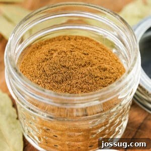 Square-cropped image of homemade apple pie spice in a small glass jar