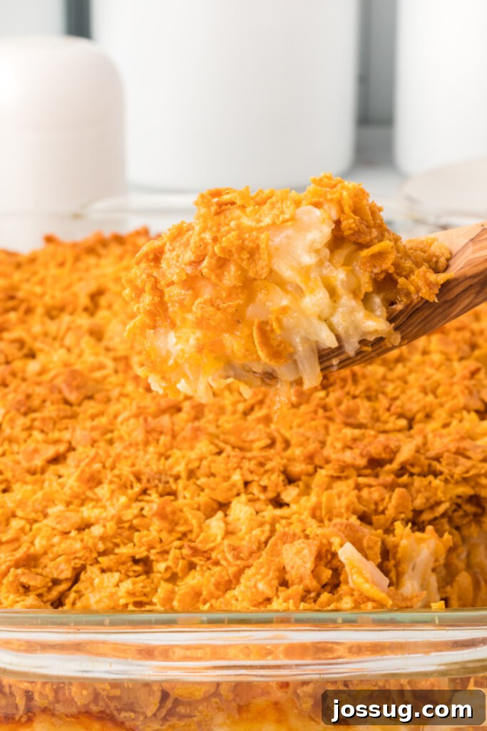 Scooping out a generous portion of cheesy hash brown casserole
