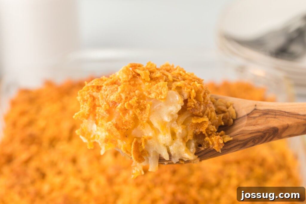 Funeral potatoes being served with a wooden spoon