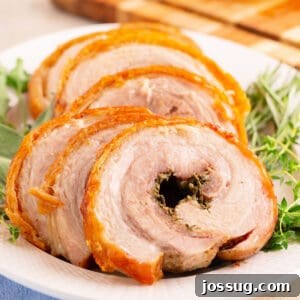 Crispy Porchetta Perfection 16 Overhead shot of plated porchetta slices with rosemary and thyme on the side, highlighting the golden skin