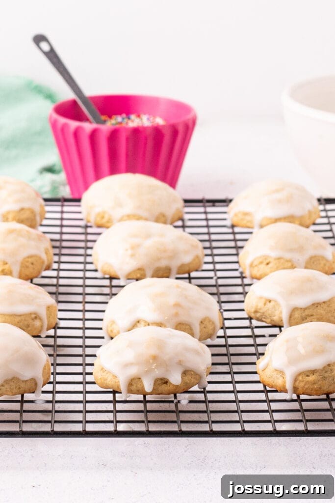 Pillowy Italian Ricotta Cookies 15 Glazed ricotta cookies setting on a cooling rack, perfectly coated and ready for sprinkles