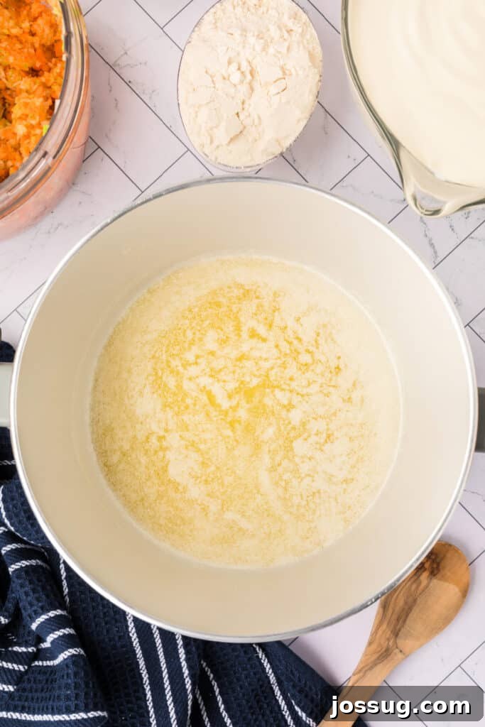 Rich golden butter has just melted in a pristine white Dutch oven on the stove, creating a shimmering pool, perfectly ready for the addition of pureed vegetables to begin building the soup's base.