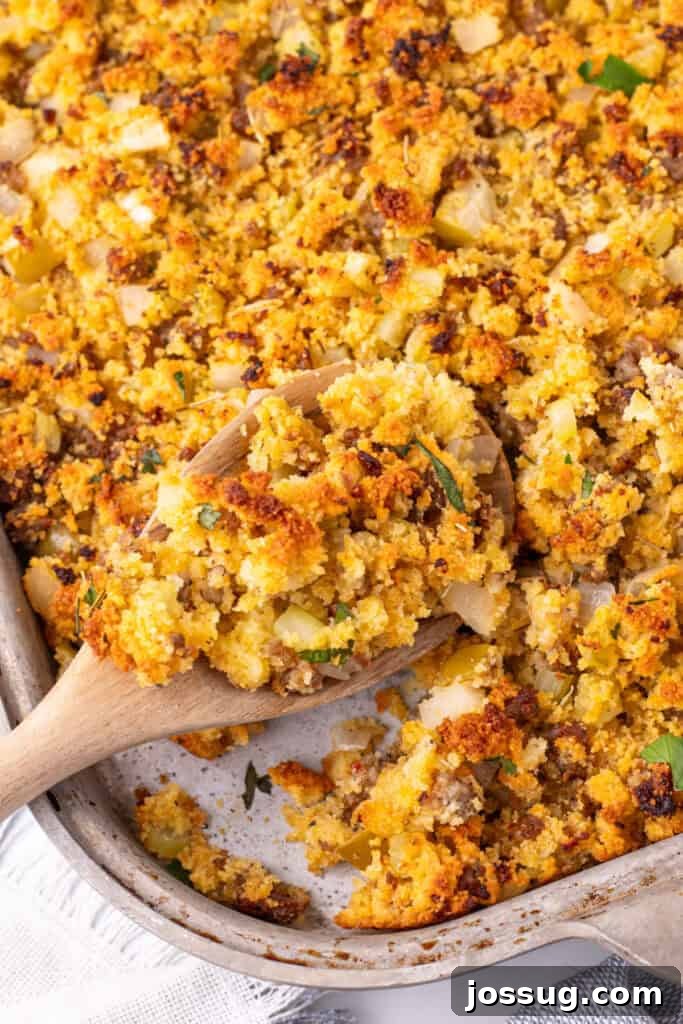 Homestyle Cornbread Dressing 2 Wooden spoon scooping warm Southern cornbread dressing from the pan, highlighting the browned edges, veggies, and tender crumbled cornbread.