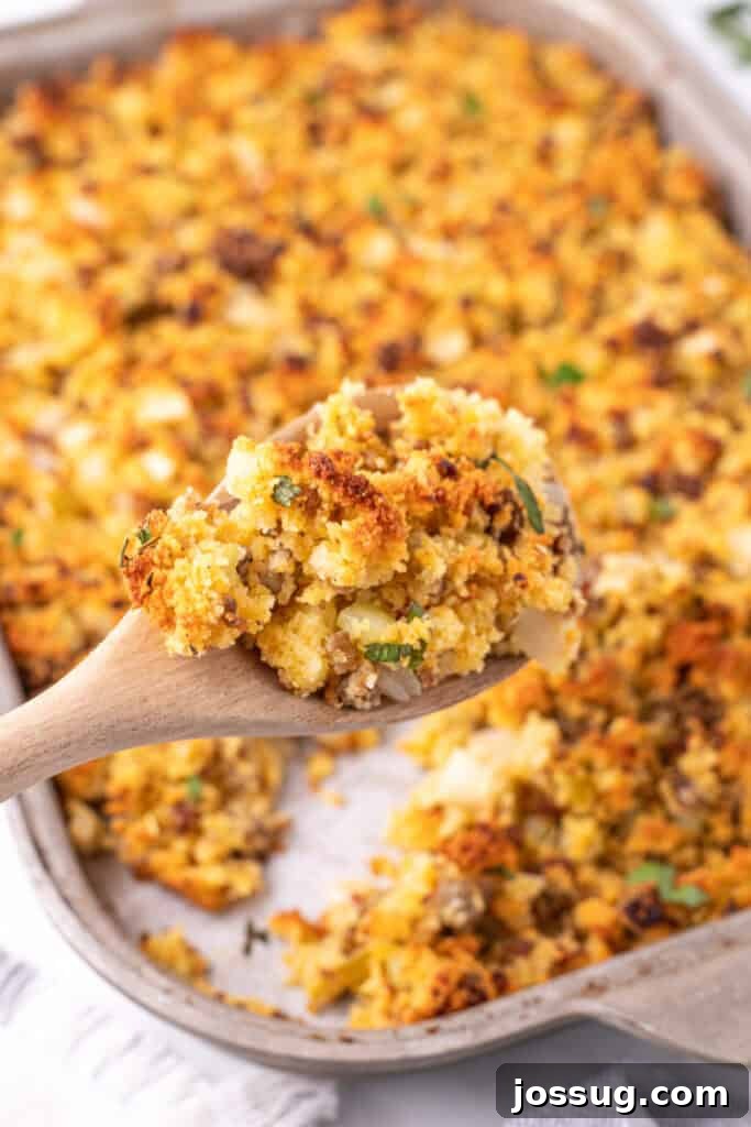 Homestyle Cornbread Dressing 11 Spoonful of golden brown cornbread dressing lifted from the baking dish showing texture of sausage, veggies, and cornbread crumbs.