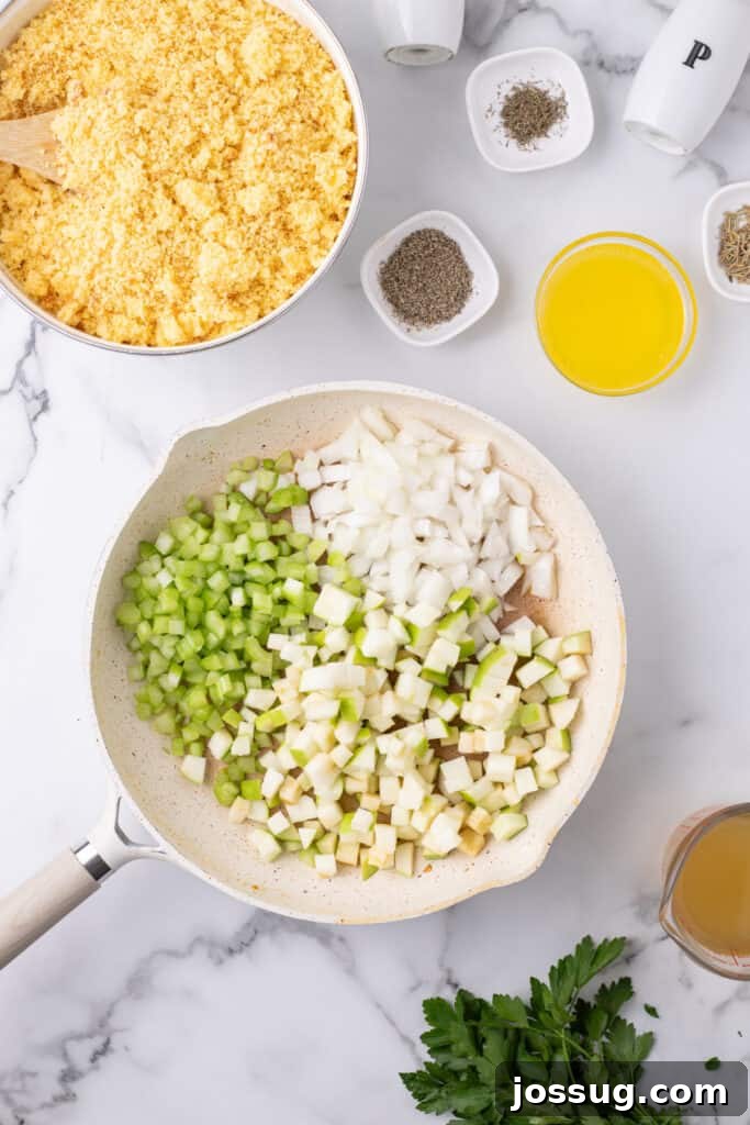 Homestyle Cornbread Dressing 5 Skillet filled with raw diced onions, celery, and apples placed beside a bowl of crumbled cornbread and small bowls of herbs.