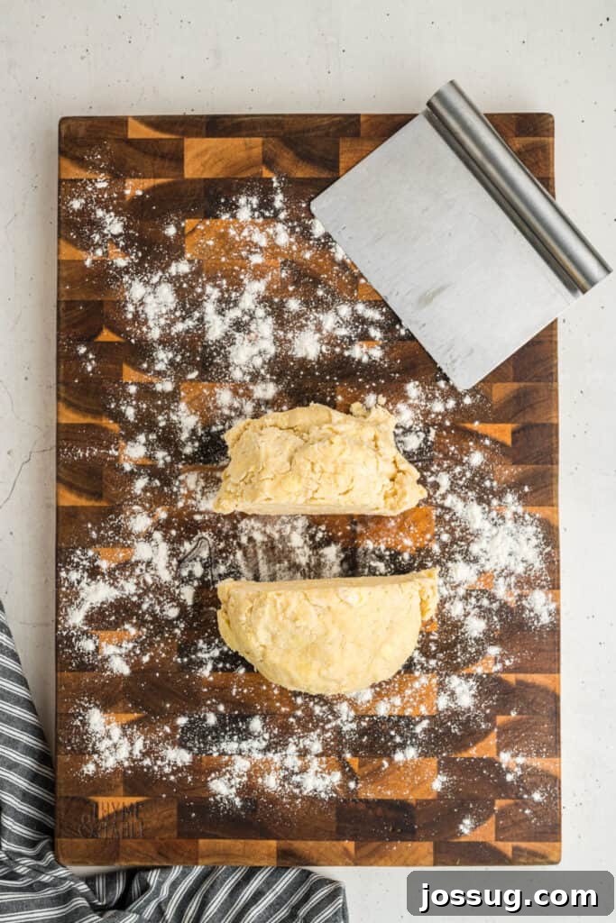 Butter pie crust dough cut in half on floured board, ready to shape