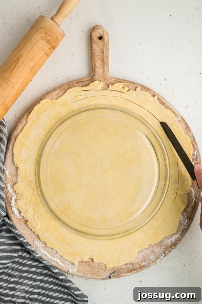 Knife trimming the edges of pie dough using the pie plate as a guide
